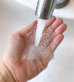 Cropped image of hand holding wet glass