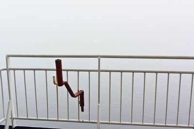 Metallic railing against sky during foggy weather