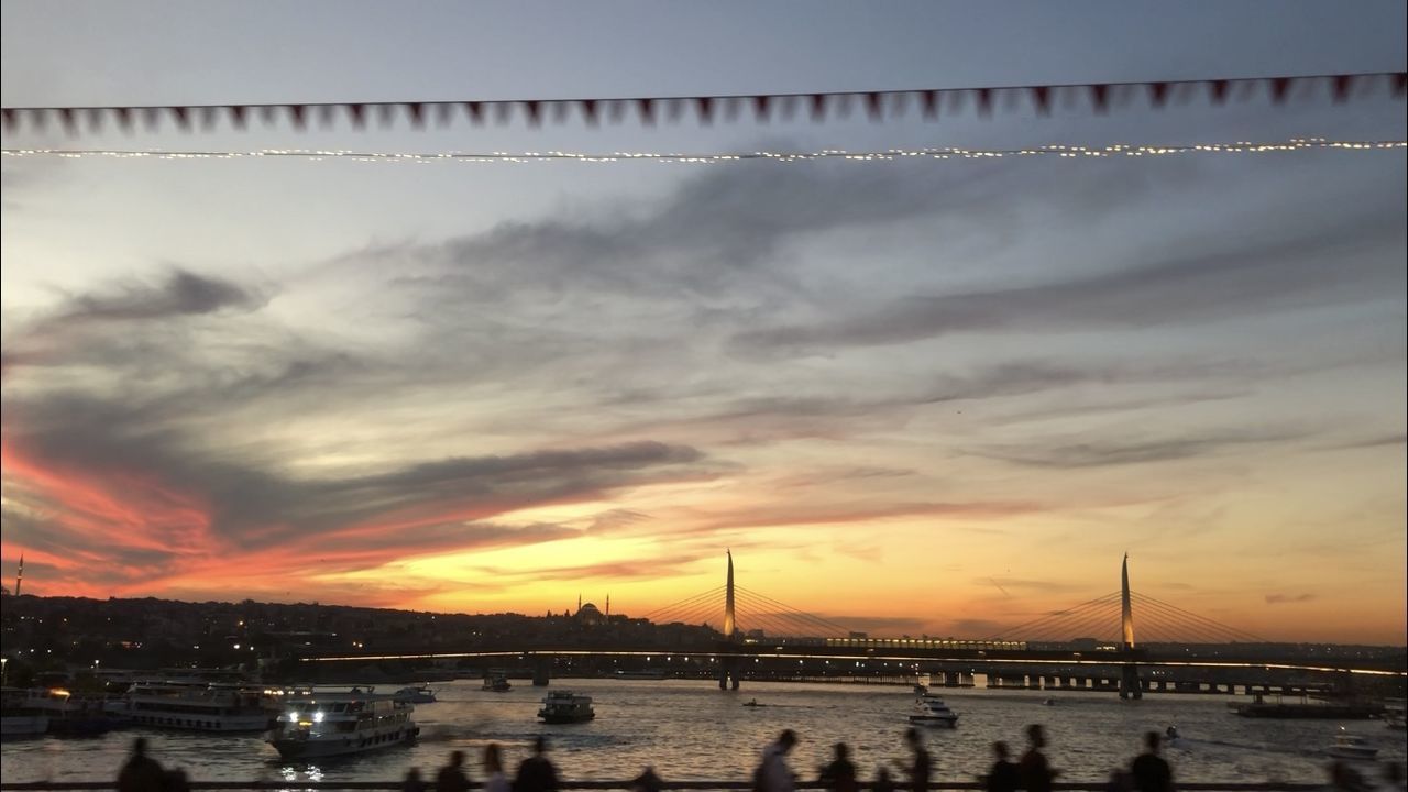 SILHOUETTE OF BOATS IN SEA AGAINST CLOUDY SKY DURING SUNSET