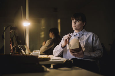 Businesswoman with food box working late in office at night