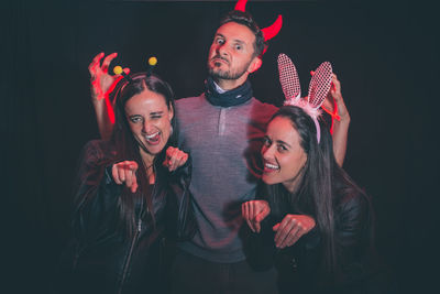 Portrait of smiling mid adult friends wearing halloween costume against back background