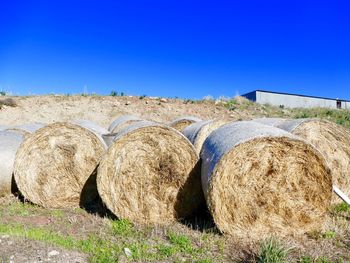 Hay bales on field against clear sky