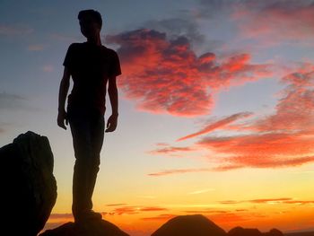 Silhouette of man on cliff during sunset