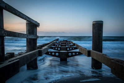 Pier over sea against sky during sunset