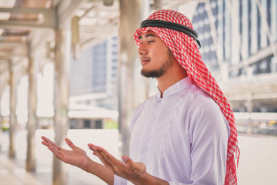 Handsome young man praying while standing on elevated road