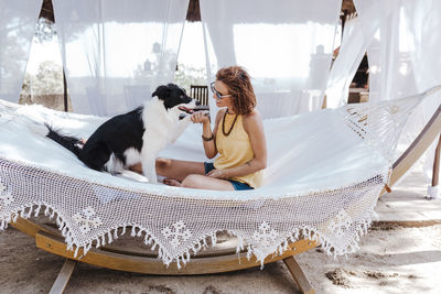 Rear view of woman with dog sitting outdoors