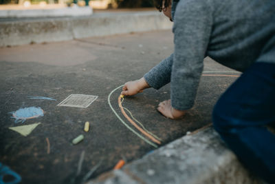 Midsection of girl drawing on road