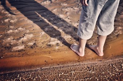 Low section of boy standing on shore