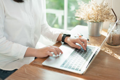 Midsection of woman using laptop on table