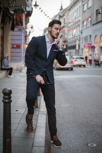 Portrait of businessman talking on mobile phone while standing in city