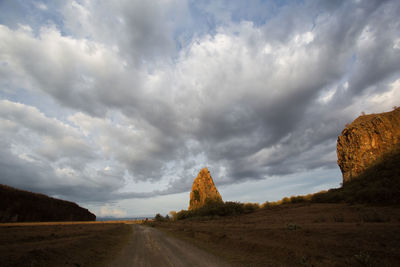 Road amidst storm clouds over landscape against sky