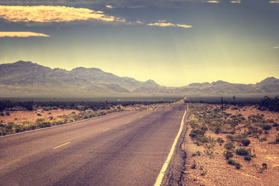 Road leading towards mountains against sky