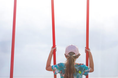 Little girl swinging on swing on playground. gray sky. kids summer game. girl have fun on summer