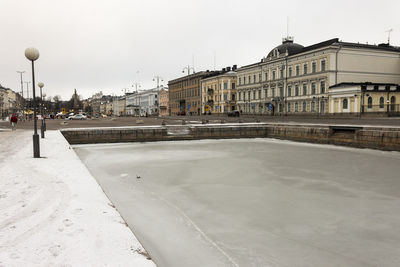 Street by buildings in city against clear sky