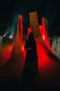 Silhouette woman standing against red illuminated structure