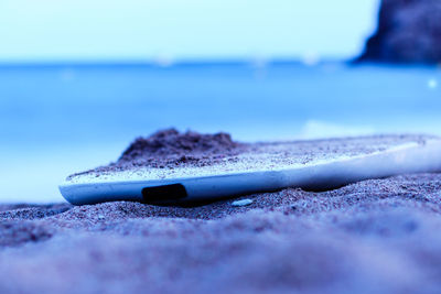 Close-up of sunglasses on retaining wall against sea