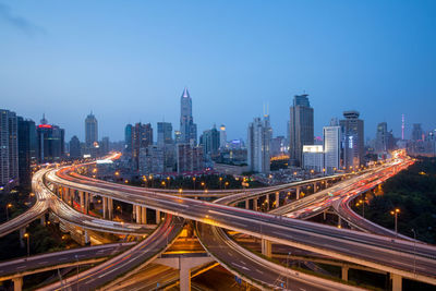 High angle view of light trails on road amidst buildings in city against sky