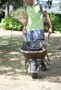 Gardener man in dirty work clothes, rolls a rusty cart with a bucket,spring work