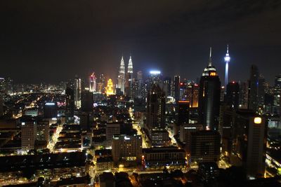 Illuminated buildings in city against sky at night