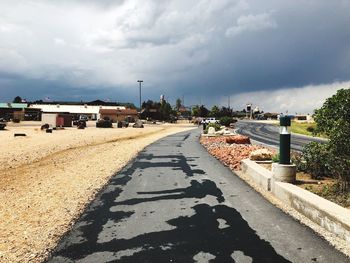 Road by buildings in city against sky