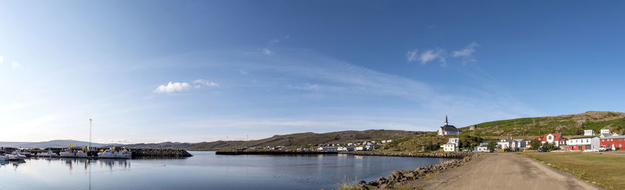 Panoramic view of road by buildings against blue sky