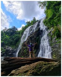 Rear view of man standing against waterfall