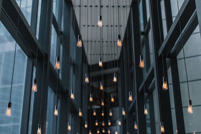 Low angle view of illuminated light bulbs hanging from ceiling