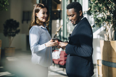 Businesswoman showing mobile phone to male colleague during conference