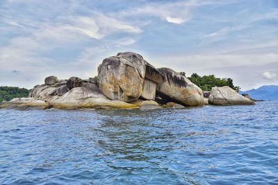 Rock formation in sea against sky