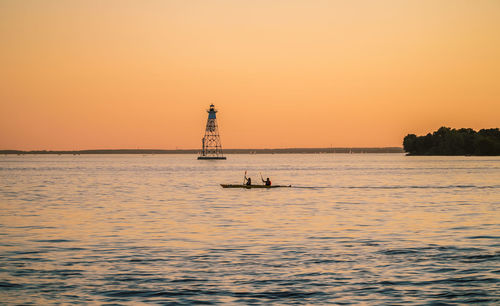 Scenic view of lighthouse on sea against sky during sunset