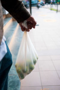 Midsection of man holding ice cream in city