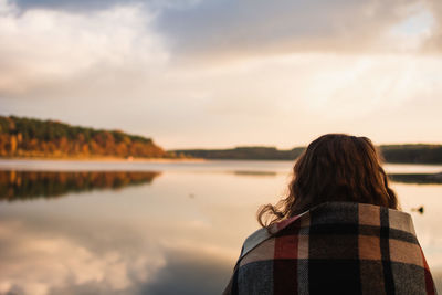 Rear view of woman standing against sky during sunset