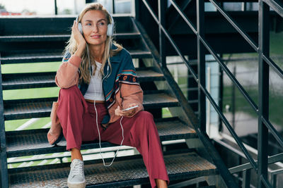 Portrait of young woman sitting on escalator