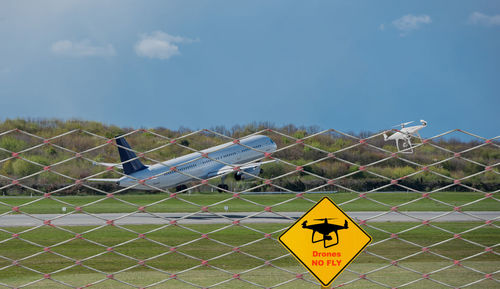 Information sign on fence against sky