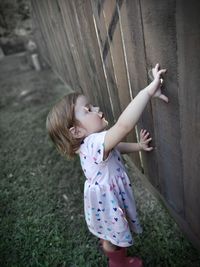 Little blonde toddler playing by the fence 