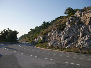 Road by trees against clear sky