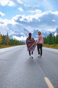 Rear view of people on road against sky