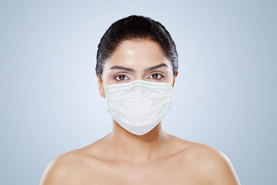 Portrait of beautiful woman wearing mask against colored background