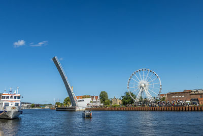 Ferris wheel in amusement park against blue sky