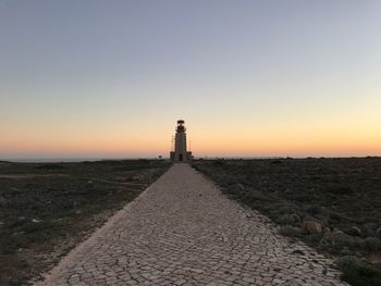 Lighthouse by sea against clear sky during sunset at sagres