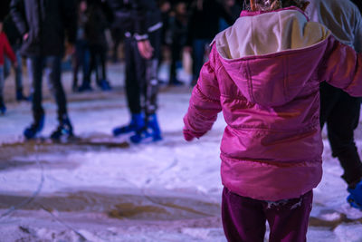 Rear view of girl in pink warm clothes standing on snow