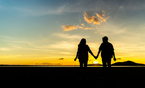 Silhouette man standing on beach against sky during sunset