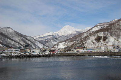 Scenic view of lake by snowcapped mountains against sky