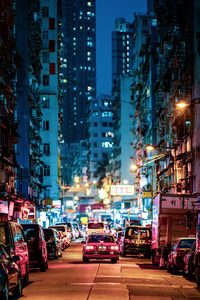 Traffic on city street amidst buildings at night