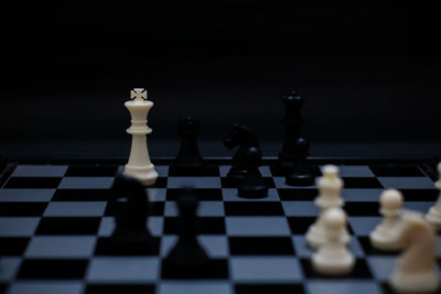 Close-up of chess pieces on board against black background