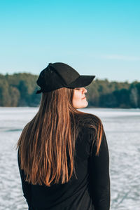 Young female woman back to the camera with long hair in a snow landscape. happy hipster girl