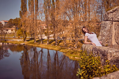 Smiling woman looking away while standing by stone wall