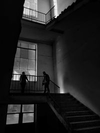 Low angle view of silhouette people standing on staircase against building