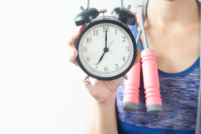 Midsection of woman with jumping rope showing alarm clock