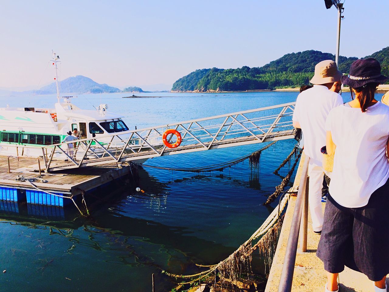 water, nautical vessel, transportation, boat, lifestyles, mode of transport, sea, clear sky, leisure activity, men, travel, moored, railing, pier, day, vacations, casual clothing, person